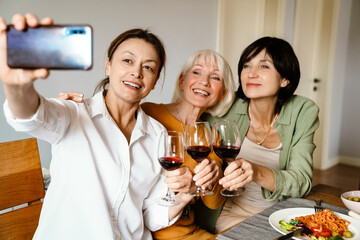 Mature three women taking selfie photo and drinking wine