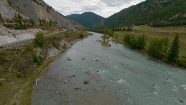 FPV sports drone shot picturesque cloudscape valley natural mountain river water stream and highway near rock. Aerial view turning amazing nature scenery wilderness environment park hilly terrain 4k