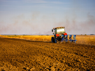 Fototapeta premium Farmer in tractor plowing preparing stubble field cultivating for seeding crops.