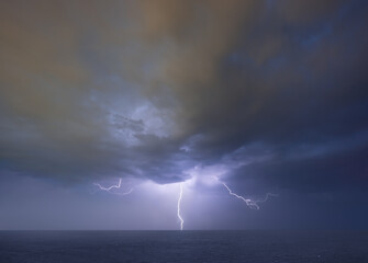 Naklejka na ściany i meble Lightning thunderstorm on stormy dark sky over the sea