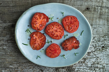 Slices of blue sea tomato on a plate on a rustic wooden background. Top view.