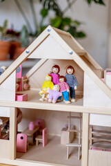 Montessori material. Large wooden doll house with a doll family inside.