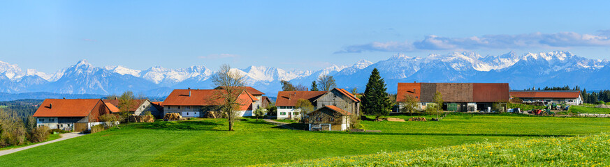 Fototapeta na wymiar Idyllisch gelegener Weiler im Allgäuer Alpenvorland vor der imosanten Kulisse der Bayerischen Alpen