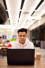 Obraz premium Portrait of handsome young cool man using laptop at coffee shop