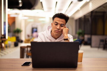 Portrait of handsome young cool man using laptop at coffee shop