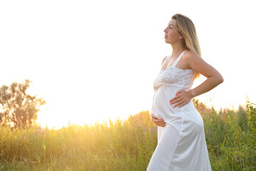 Fototapeta na wymiar Outdoor pregnancy portrait: beautiful young pregnant female anticipate child, enjoy nature. Happy future mother expecting a baby soon
