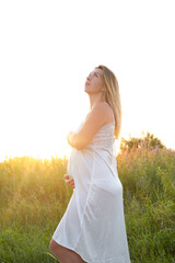 Fototapeta na wymiar Outdoor pregnancy portrait: beautiful young pregnant female anticipate child, enjoy nature. Happy future mother expecting a baby soon