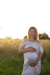 Fototapeta na wymiar tender pregnancy portrait on sunset. expecting mother to be outside in pink dress. Beautiful tender mood photo of pregnancy.