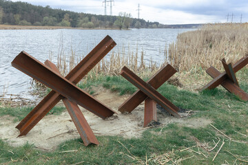 Anti-tank hedgehogs on the shore of a wide lake