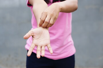 Woman scratching arm from itching on light gray background. Cause of itchy skin include insect...