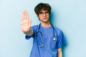 Young caucasian nurse man isolated on blue background standing with outstretched hand showing stop...