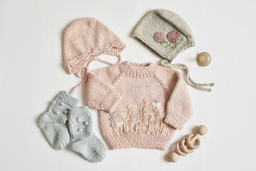 Children's knitwear. Jumper, hat, booties, socks. Wooden teether, nipple. Baby shower party. Preparing for childbirth. Flat lay.