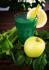 crystal glass with detox smoothie made with spinach, celery, lemon and apple on wooden background