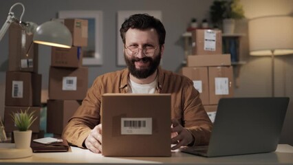 Smiling man with box looks at camera and shows thumb up. Happy regular customer of online store. Online shopping with home delivery