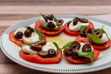 Selective focus of a tomato, bocconcino, basil and olive salad.
