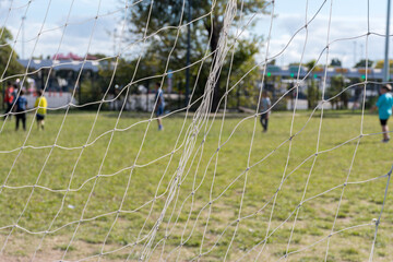 Selective focus on the net of a soccer goal and ground game.