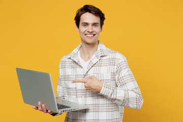 Young smiling happy copywriter freelancer man 20s in white casual shirt hold use work point finger...