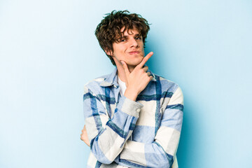 Young caucasian man isolated on blue background unhappy looking in camera with sarcastic expression.