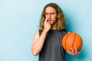 Young caucasian man playing basketball isolated on blue background relaxed thinking about something looking at a copy space.