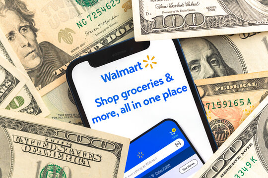 Walmart app logo on mobile phone screen. Business background with laptop and money photo