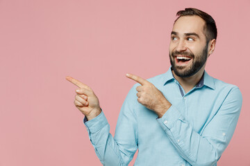 Young smiling fun happy cool man 20s in classic blue shirt point index finger aside on workspace...