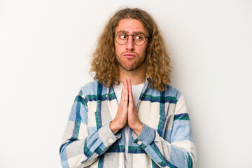 Young caucasian man isolated on white background praying, showing devotion, religious person looking for divine inspiration.