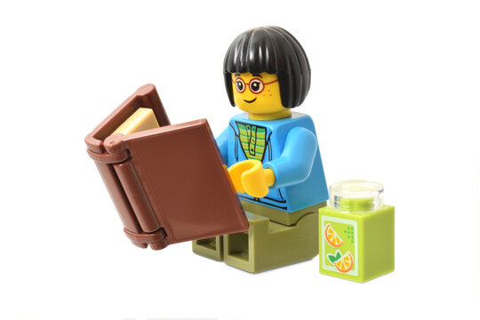Lego minifigure with a book isolated on white. Editorial illustrative image of reading and learning.