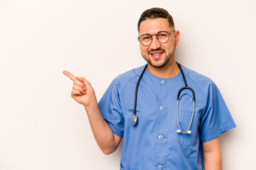 Hispanic nurse man isolated on white background smiling and pointing aside, showing something at blank space.