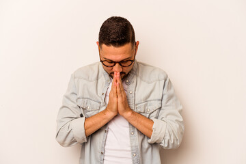 Young hispanic man isolated on white background praying, showing devotion, religious person looking...