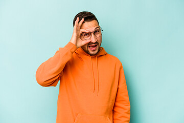 Young hispanic man isolated on blue background excited keeping ok gesture on eye.
