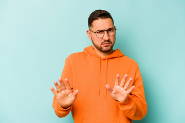 Young hispanic man isolated on blue background rejecting someone showing a gesture of disgust.