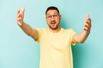 Fototapeta premium Young hispanic man isolated on blue background celebrating a victory or success, he is surprised and shocked.