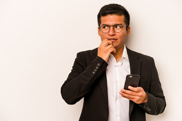 Young business hispanic man holding mobile phone isolated on white background relaxed thinking about something looking at a copy space.