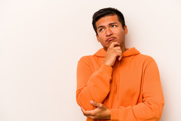 Young hispanic man isolated on white background looking sideways with doubtful and skeptical...