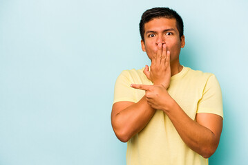 Young hispanic man isolated on blue background pointing to the side