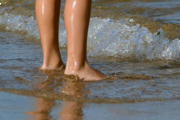 Legs of the girl walking among the small waves of the sea.
Legs of a girl running to the ocean on a sandy beach.
Close-up Girl's Legs In Shallow Water.