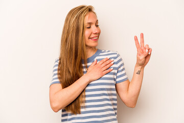 Young caucasian woman isolated on white background taking an oath, putting hand on chest.
