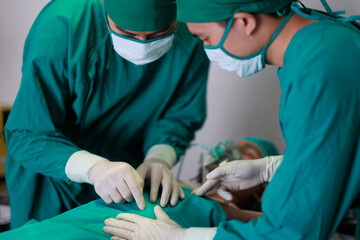 Two Asian surgeons doctor working together on a surgery with male patient  in operation room.