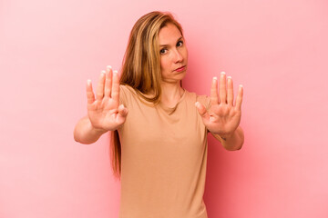 Young caucasian woman isolated on pink background standing with outstretched hand showing stop...