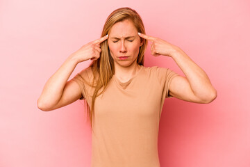 Young caucasian woman isolated on pink background focused on a task, keeping forefingers pointing head.