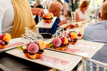 Waiter serves desserts on a tray, ice creams and cakes with delicate flavors.