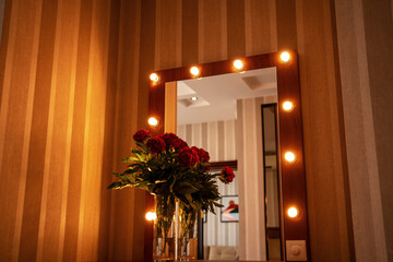 red peonies near the mirror on the bedside table