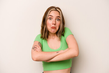 Young caucasian woman isolated on white background shrugs shoulders and open eyes confused.