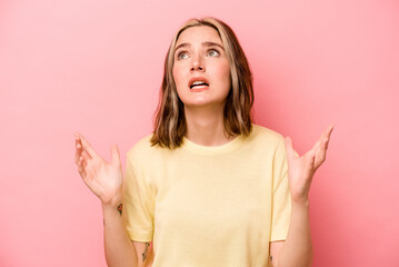 Young caucasian woman isolated on pink background screaming to the sky, looking up, frustrated.