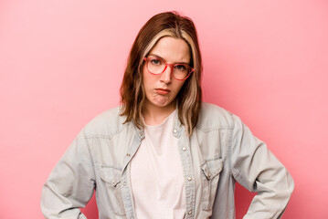 Young caucasian woman isolated on pink background sad, serious face, feeling miserable and displeased.