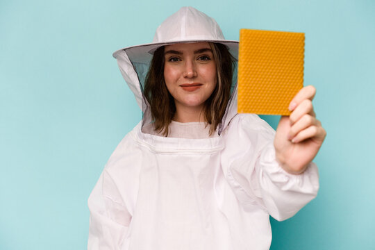 Young caucasian beekeeper woman isolated on blue background