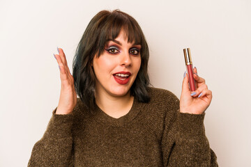 Young caucasian makeup artist woman holding a lipgloss isolated on white background receiving a...