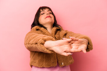 Young caucasian woman isolated on pink background stretching arms, relaxed position.