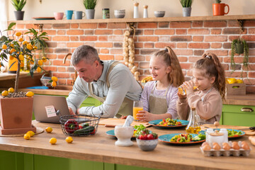 In the Kitchen: Family of Four Cooking Muffins Together. Mother and Daughter Mixing Flour and Water to Create Dough for Cupcakes, Father, daughter Preparing Paper Lines for Pans. Children Helping