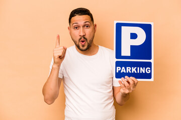 Hispanic caucasian man holding parking placard isolated on beige background having some great idea, concept of creativity.
